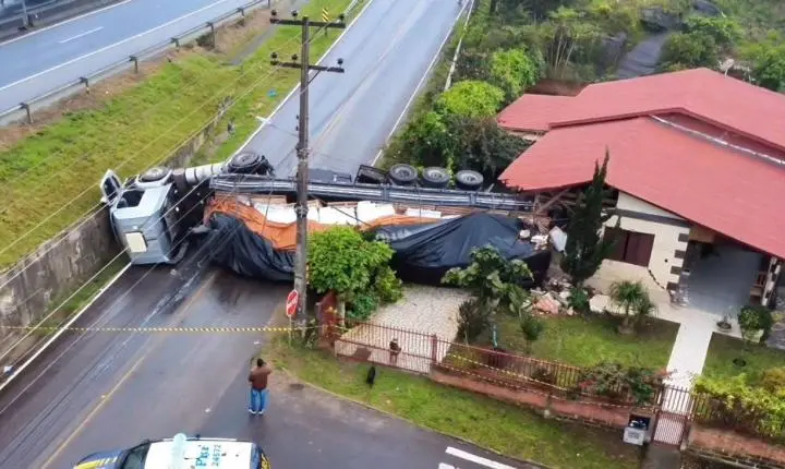 Caminhão tomba na BR-101, sai da pista e atinge residência